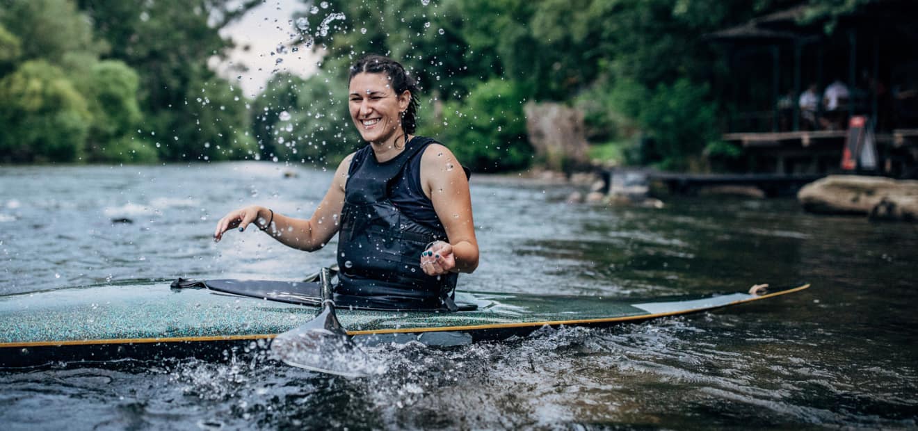 Eine Frau sitzt in einem Kajak auf einem Fluss. 