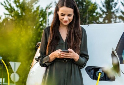 Eine Frau steht neben ihrem Elektroauto, während es lädt. 