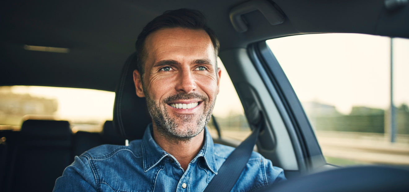 Ein Mann sitzt in einem Auto und lächelt. 