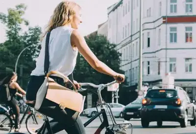 Eine Frau und ein Mann fahren auf einer stark befahrenen Kreuzung mit dem Fahrrad. 