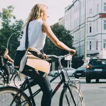 Eine Frau und ein Mann fahren auf einer stark befahrenen Kreuzung mit dem Fahrrad. 