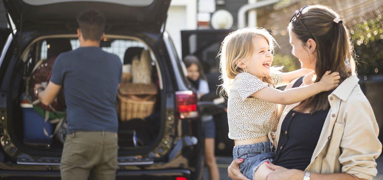 Ein Mann packt das Auto, eine Frau hält ihr Kind auf dem Arm. Jetzt zur günstigen Zweitwagenversicherung von AdmiralDirekt.