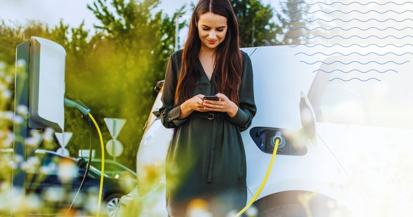 Frau wartet, während sie ihr Elektroauto lädt. 