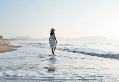 Ein Frau geht am Strand spazieren.