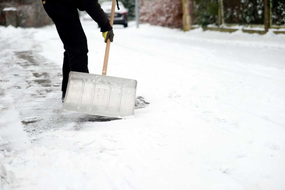 Mann räumt im Winter die Straße von Scnee frei. 