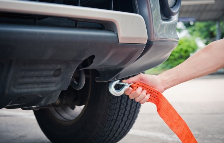 Jemand bringt ein Abschleppseil am Fahrzeug an.