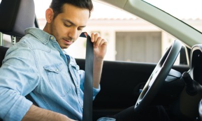 Ein Mann in einem Auto schnallt sich an. 