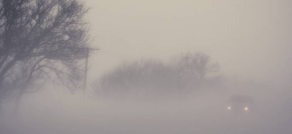 Ein Auto fährt auf einer nebeligen Straße.