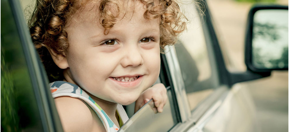 Ein glücklicher kleiner Junge schaut aus dem Auto.