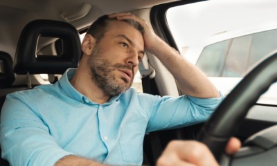 Ein Mann sitzt im Auto und rauft sich genervt die Haare.