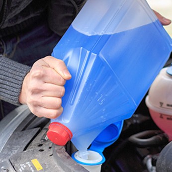 Mann füllt das Frostschutzmittel seines Autos nach. 