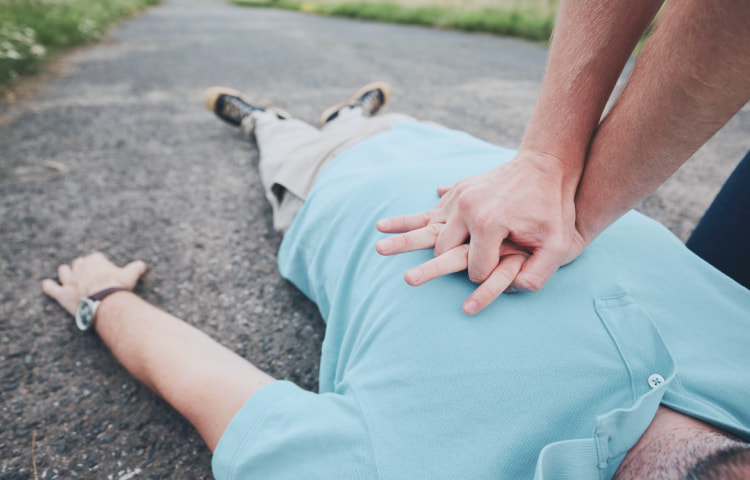 Ein Mann führt eine Herz-Rhythmus-Massage bei einer bewusstlosen Person durch