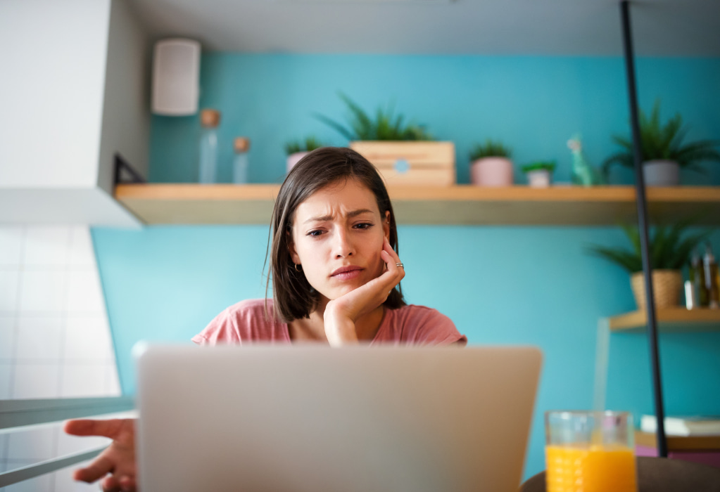 Junge Frau sitzt vor einem Laptop. 