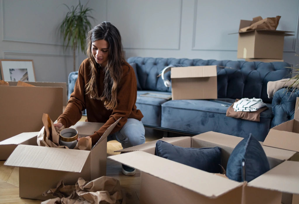 Eine Frau packt Umzugskartons in einer Wohnung.