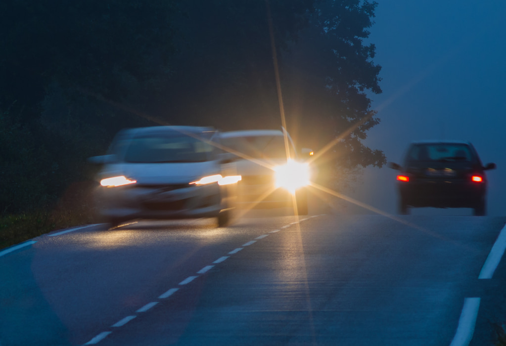 Ein Auto betätigt die Lichthupe und setzt zum Überholvorgang auf der Landstraße an. 