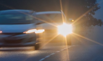 Ein Auto betätigt die Lichthupe und setzt zum Überholvorgang auf der Landstraße an. 