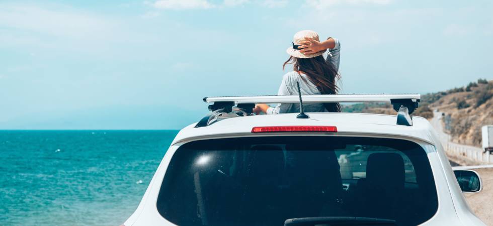 Frau mit Hut ist mit Auto im Urlaub. 