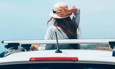 Frau mit Hut ist mit Auto im Urlaub. 