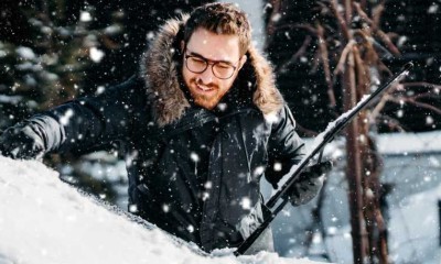 Mann kratz im Winter Eis von seinem Auto. 