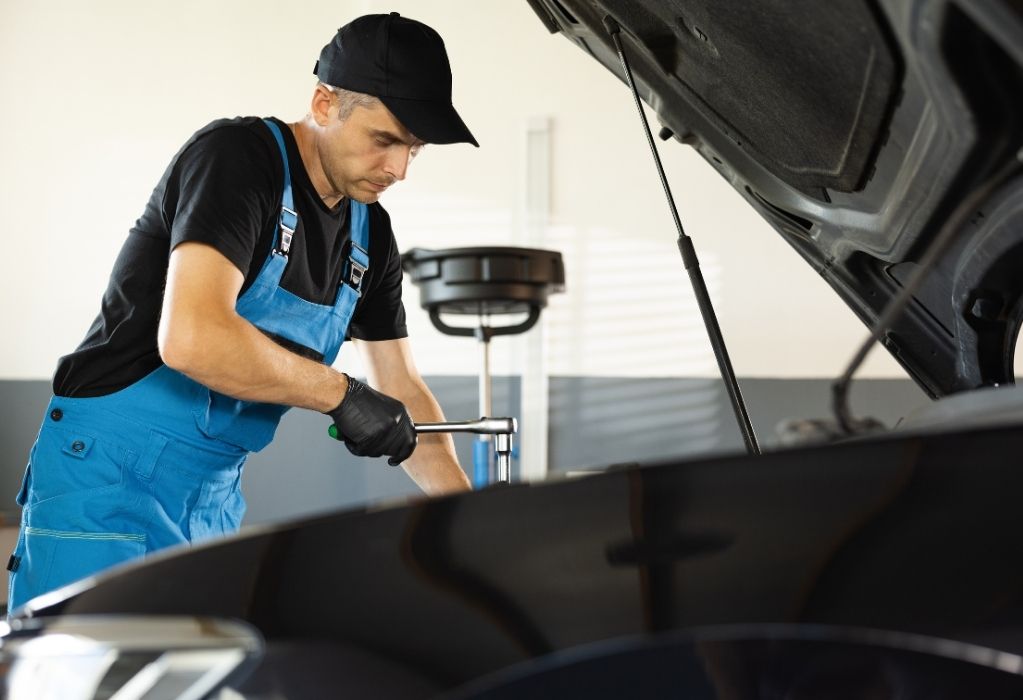 Ein Mechaniker steht vor geöffneter Motorhaube.