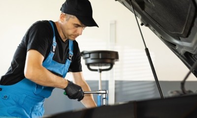 Ein Mechaniker steht vor geöffneter Motorhaube.