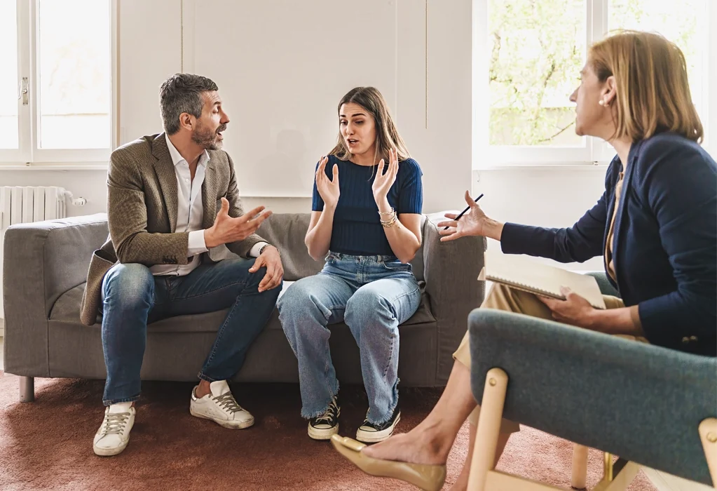 Ein Paar streitet bei einer Mediation. Die Mediatorin vermittelt in dem Konflikt. 