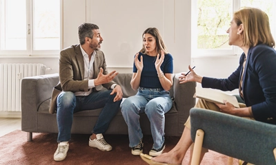 Ein Paar streitet bei einer Mediation. Die Mediatorin vermittelt in dem Konflikt. 