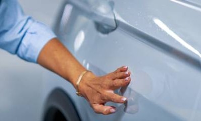 Frau erkennt Kratzer auf ihrem Auto.