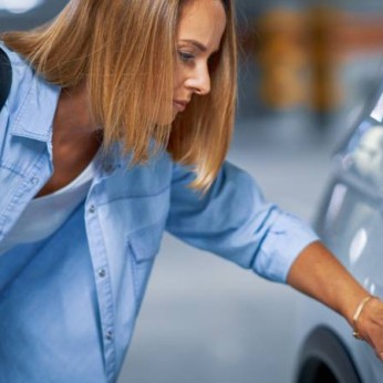 Frau erkennt Kratzer auf ihrem Auto.