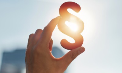 Eine Hand hält einen Paragrafen ins Licht. 