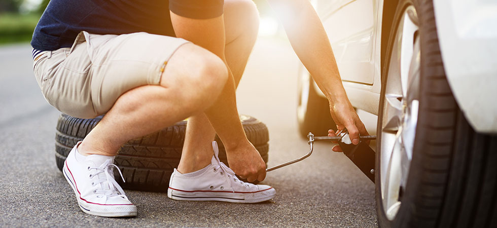 Junger Mann beim Reifenwechsel. 