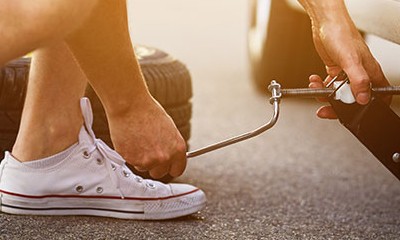 Junger Mann beim Reifenwechsel. 