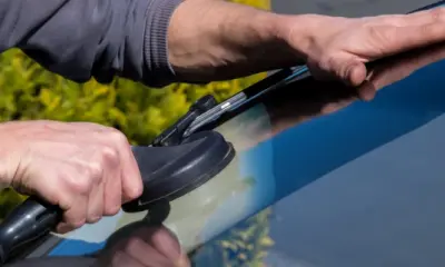 Ein Automechaniker montiert eine Windschutzscheibe an einem Auto mit einem Saugheber. 