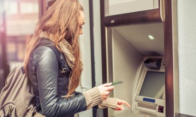 Eine junge Studentin hebt Geld am Automaten ab.