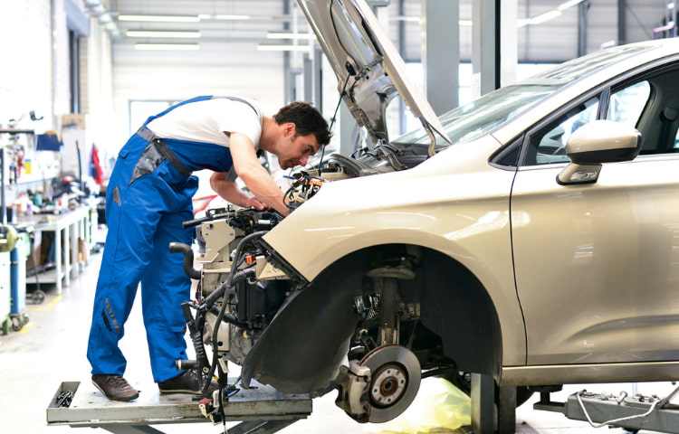Ein Mechaniker arbeitet im Motorraum eines Autos.